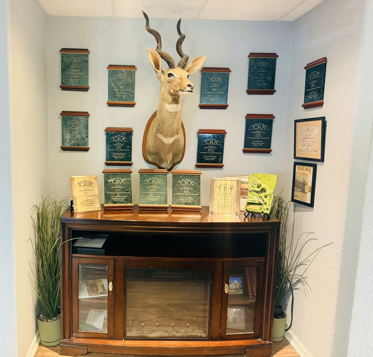 Kudu Roofing's Colorado Roofing Association awards displayed around a mounted kudu in the Littleton office